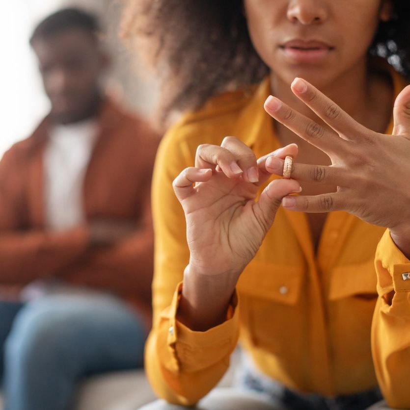 black woman taking off wedding ring sitting near husband indoors